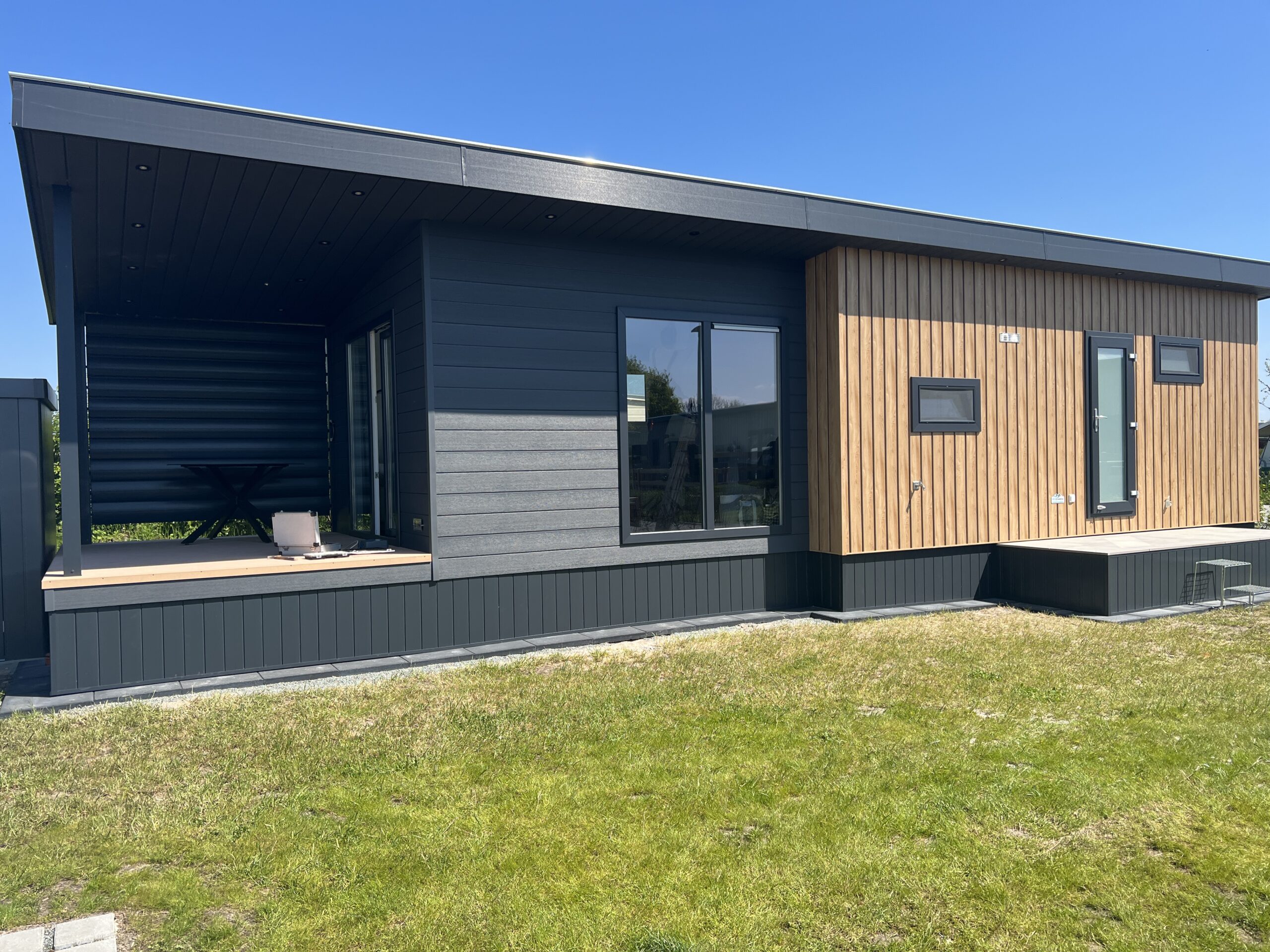 Moderner Campingplatzbau mit hochwertigem Ferienhaus in Holz- und Anthrazitoptik – Modulbau mit überdachter Terrasse und gepflegter Außenanlage.