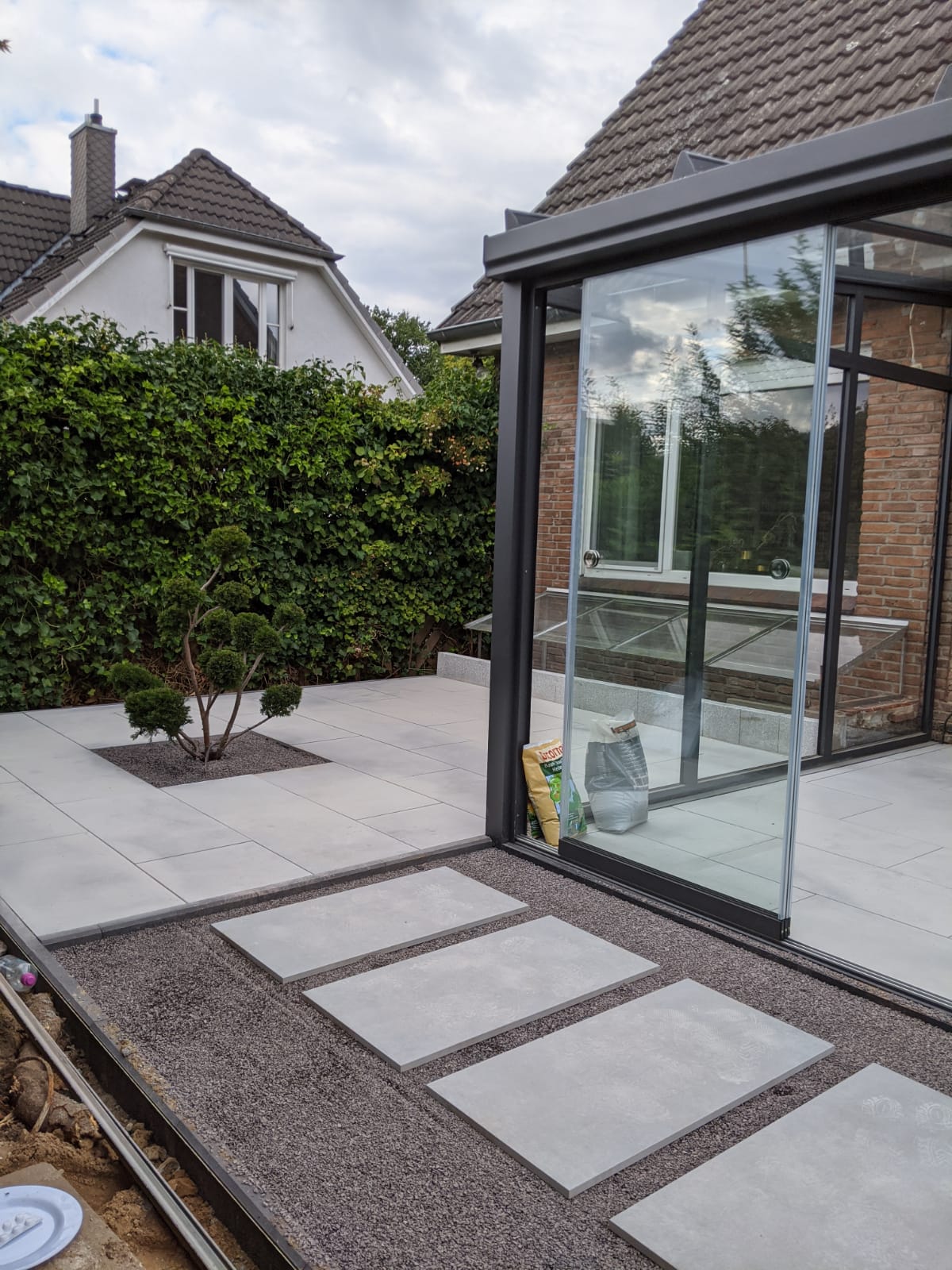 Moderner Terrassenbereich mit großformatigen hellgrauen Betonplatten und einer klaren Linienführung