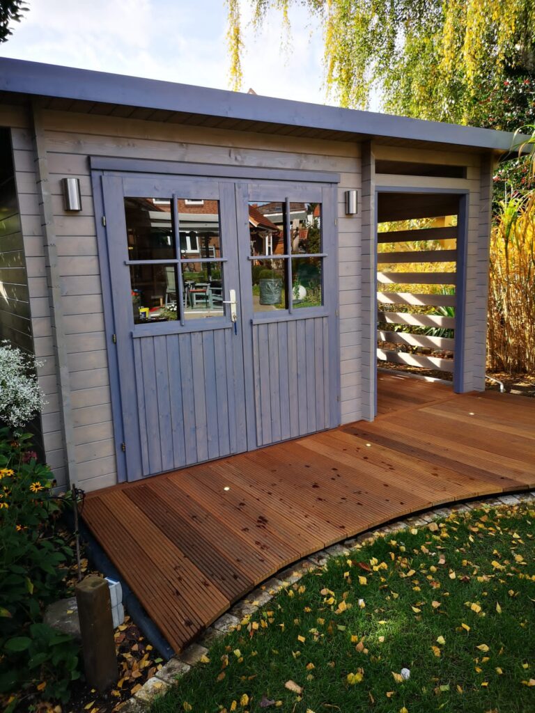 Modernes Gartenhaus aus Holz mit graublauer Lasur und doppelflügeliger Tür mit Fenstereinsätzen