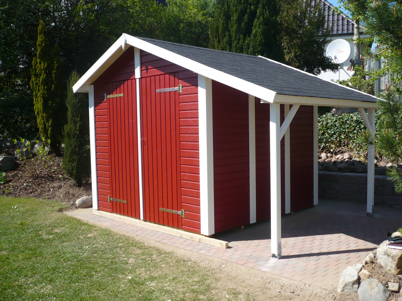Gartenhaus aus Holz mit roter Fassade und weißem Rahmen – individuell gebautes Holzhaus auf gepflastertem Fundament von HGB Holz- & Gartenbau