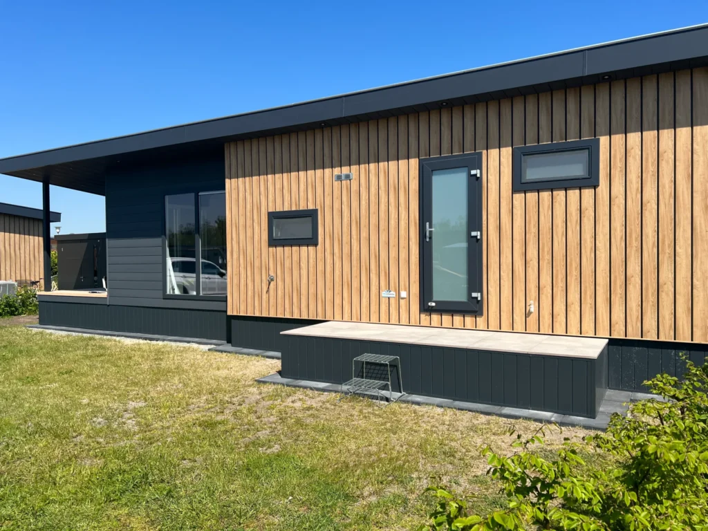 Detailansicht der modernen Holzfassade und der dunklen Sockelverkleidung eines Mobilheims, ausgeführt von HGB Holz und Gartenbau GbR.