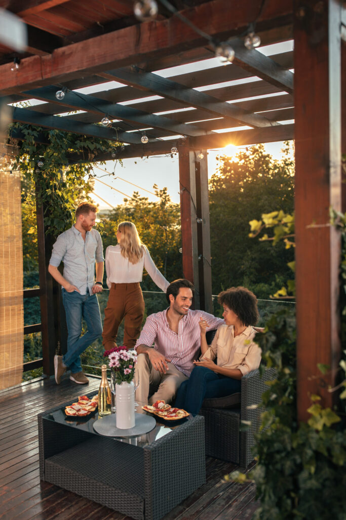 Menschen sitzen in gemütlicher Pergola Terrasse.